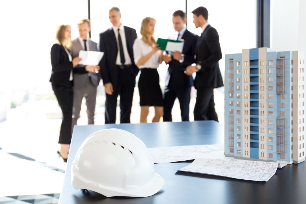Mitig8 AI:Business meeting of architects and investors, model of modern multi storey residential building house and hardhat on table , construction planning concept